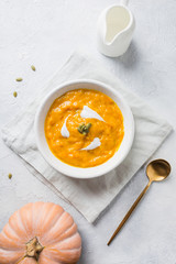 Pumpkin soup with cream on grey stone background. Top view.