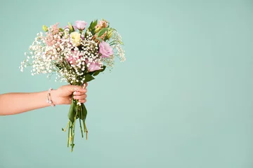 Rolgordijnen Female hand with bouquet of beautiful flowers on color background © Pixel-Shot