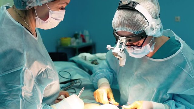 A medical team of surgical specialists working in the modern operating room of the hospital, performing team preparation of the patient for surgery.