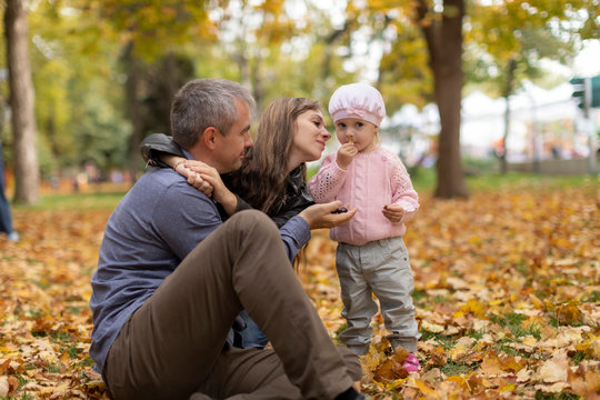 Happy family together in autumn garden/park. Parents with their children are sitting on coverlet in park. Outdoor in full height photo. Family concept