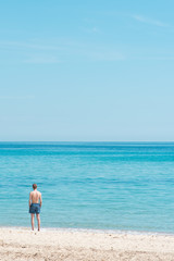 un homme sur la plage regardant la mer en été pendant les vacances