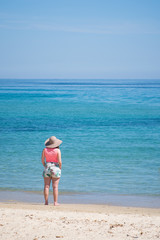 une femme sur la plage au bord de la mer regarde l'horizon