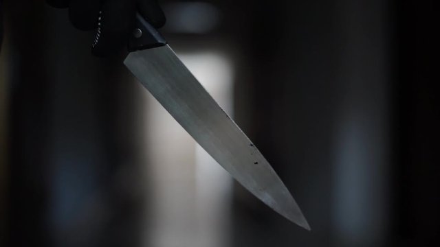 Close up of Hand with knife walking in the apartment. man Bandit is holding a knife in hand, Threat Concept, Murder concept.