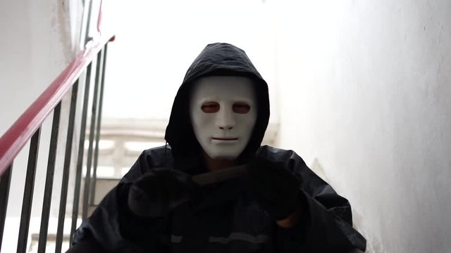Hacker wearing a white mask and hoodie holding credit card and using smartphone. Cyber crime concept, Data thief, internet attack, darknet and cyber security concept.