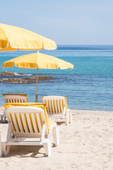 des chaises longues, des transats, des parasols sur une plage avec vue sur la mer pour les vacances