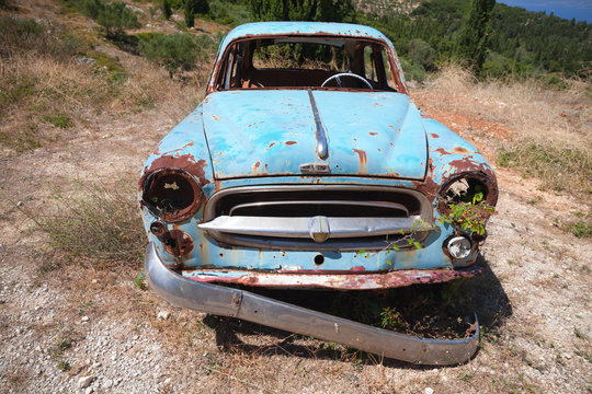 Old abandoned rusted car stands in summer