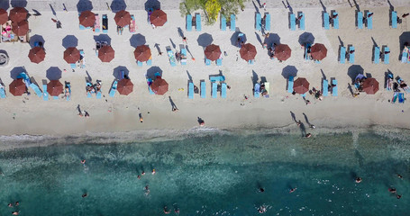 Top view of sandy beach with turquoise sea water and brown umbrellas, aerial drone shot.