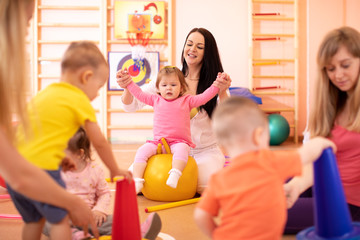 Yoga for baby. Child-friendly fitness for women with kids. Mothers with happy toddlers doing...