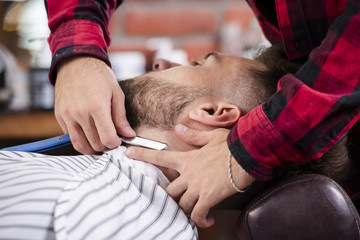 Obraz na płótnie Canvas Hairdresser shaving a beards man in barber shop