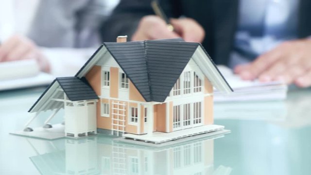 Businessman signs contract behind home architectural model