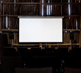 Weiße Leinwand in alten Holzschuppen. White projection screen in old wooden barn. Kino in Holzscheune. - obrazy, fototapety, plakaty