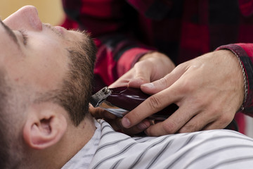 Young man arranging his beard with a shaving machine