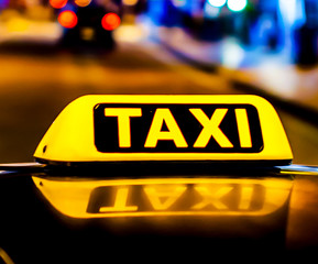Yellow taxi sign on a taxi car roof at night