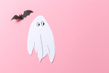 White ghost costume against a pastel pink background. Minimal Halloween scary concept. craft paper...
