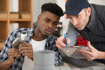 young plumber with manager working on pipes