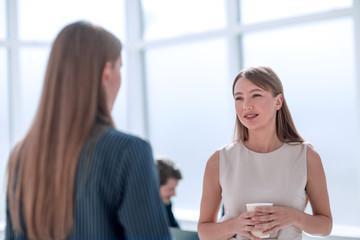 businesswoman with a glass of coffee discussing something with her colleague