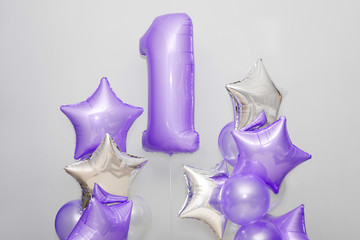 Decoration for 1 years birthday, anniversary. Bunch of gel-shaped violet balloons and stars on...