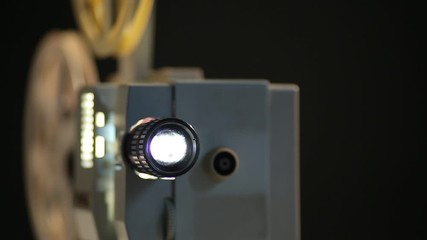 the old movie projector works on a dark background the front view is 8 millimeters the film in two reels from the lens there is light