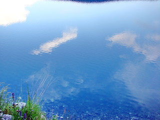 A view of the transparent surface of a mountain lake, which reflects the clouds of heaven and through which the bottom is visible.