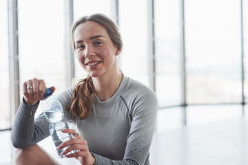 Positive girl taking a break. Sportive young woman have fitness day in the gym at morning time