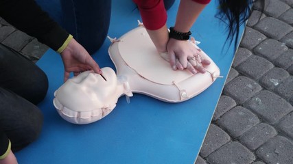 Woman volunteer instructs  technique of a cardiopulmonary resuscitation, medical training