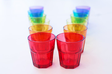 multi-colored glass on a white background. containers made of glass, ordered by the rainbow color spectrum, isolated, purple, blue, green, yellow, orange, red, with clipping path.