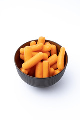 Raw Organic Orange Baby Carrots on black bowl, isolated white background