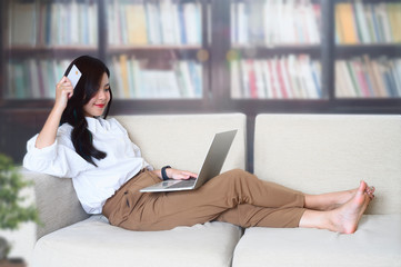 woman shopping online at home, using laptop and credit card.