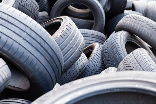 Close-up of used and old car tires with worn down treads randomly piled up in a stack