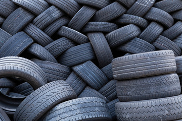 Close-up of a stack of old car tires with worn down profiles piled up in an interwoven pattern