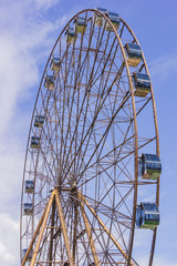 Ferris wheel in sunny summer Sochi on blue cloudy sky background