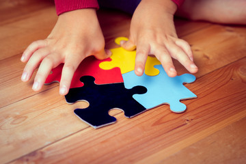 Close up: An autistic child's hands playing a puzzle symbol of Public awareness for autism spectrum...