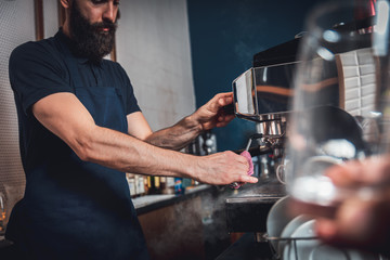 Barista preparing cappuccino on espresso machine for customer in coffee shop.