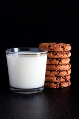 COOKIES WITH CHOCOLATE CHIPS WITH MILK GLASS ON BLACK BACKGROUND