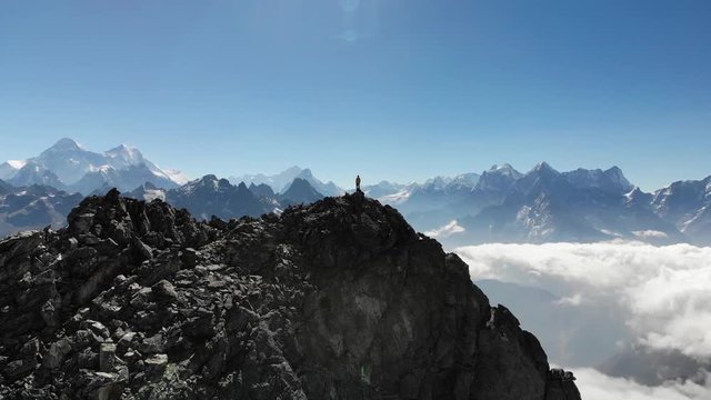 Mountaineer standing on mountaintop with view over Everest