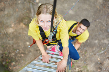 Junge Frau im Kletterpark angeseilt auf der Leiter