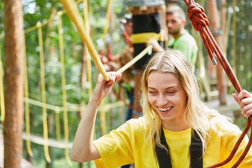 Frau im Hochseilgarten geht mutig über eine Brücke