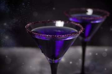Two glasses with purple cocktail for Halloween party on the dark background