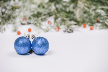Blue Christmas balls on snow with fir branches