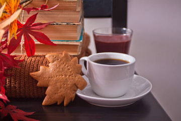 Cup of coffee, autumn leaves, cookies. old books on the wooden black chair. Autumn harvest. Autumn concept.