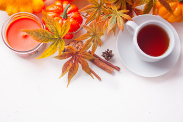 Cup of tea, autumn leaves, candle, pumpkin on the white background. Autumn harvest. Autumn concept. Top view. Copy space