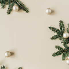 Christmas / New Year holiday composition. Mock up frame with blank copy space, fir needle branches, Christmas baubles on beige background. Flat lay, top view festive concept.