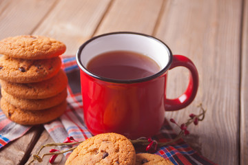 Cookies with red mug of hot tea or coffee on the wooden table