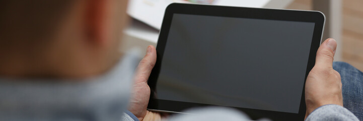 Male hand holds tablet in home setting while