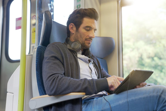 young man watching a movie on a tablet in a train