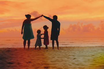 Happy parents making home for kids at sunset beach, family care