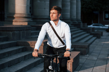 Confident in future. Businessman in formal clothes with black bicycle is in the city