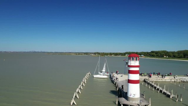 Aerial drone shot of a lighthouse on a lake. Camera moving forward  passing by the lighthouse and a boat.