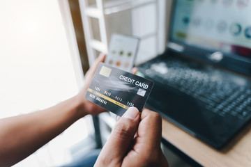 Man holding mock up credit card with number using smartphone and laptop computer for shopping.Online shopping concept.