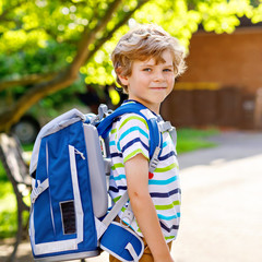 Happy little kid boy with glasses and backpack or satchel on his first day to school or nursery....